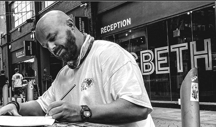 Luke Staton writing at a cafe table.