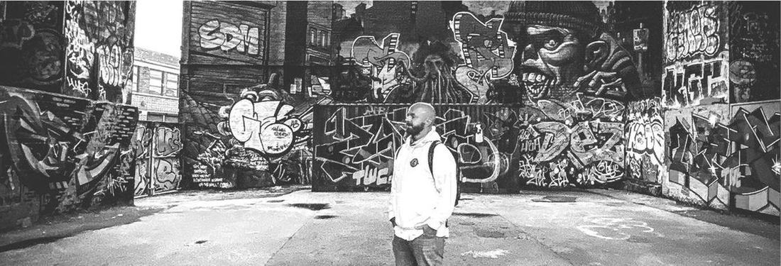 Luke Staton standing in front of a graffiti wall.